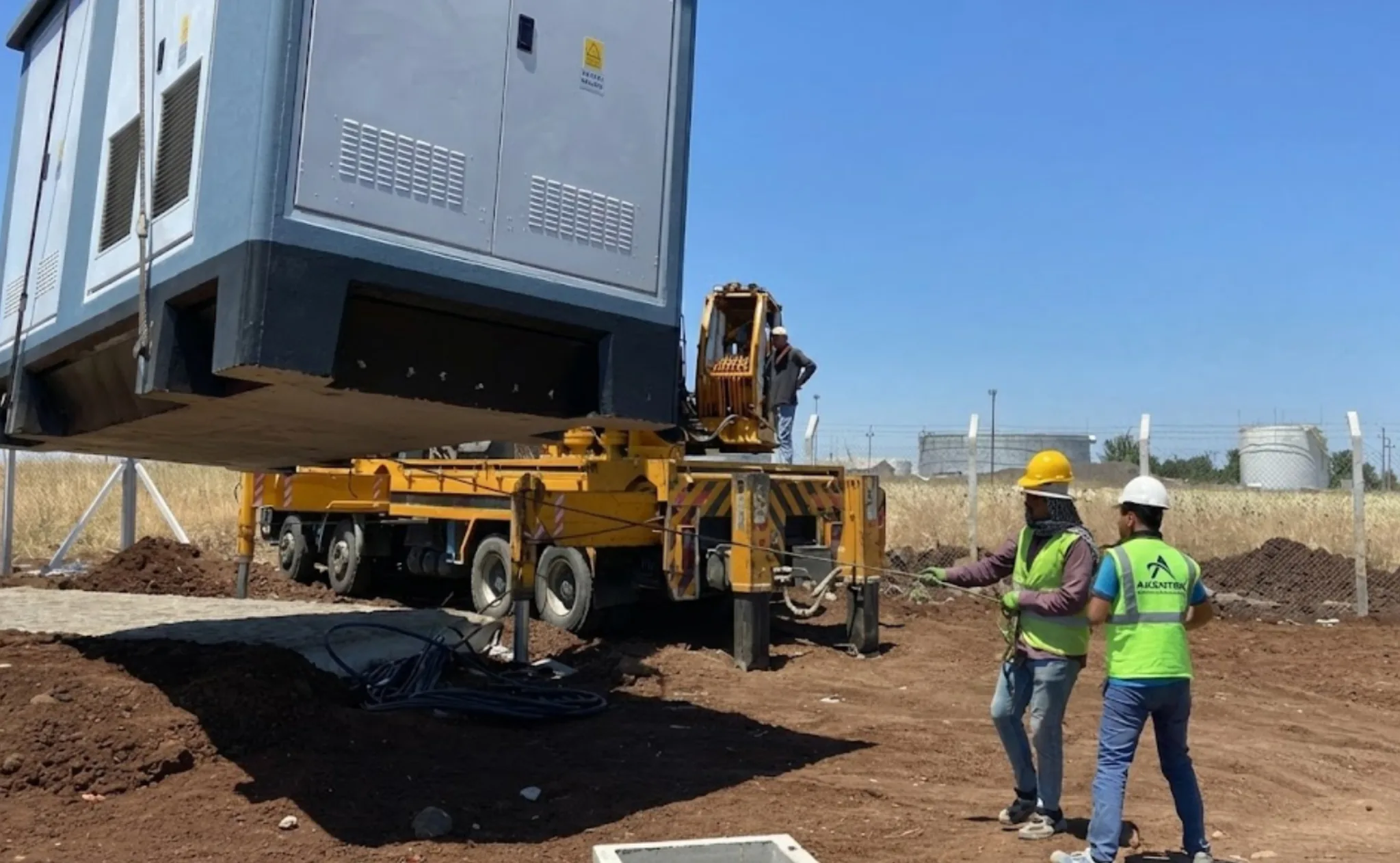Vinç yardımıyla sahaya yerleştirilen modüler trafo merkezi ve AKENTEK saha ekibi.